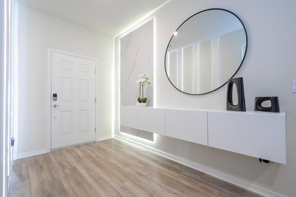 A modern entryway features a floating white console, a round mirror, and a backlit marble panel — 4117 LANA AVENUE, DAVENPORT, FL