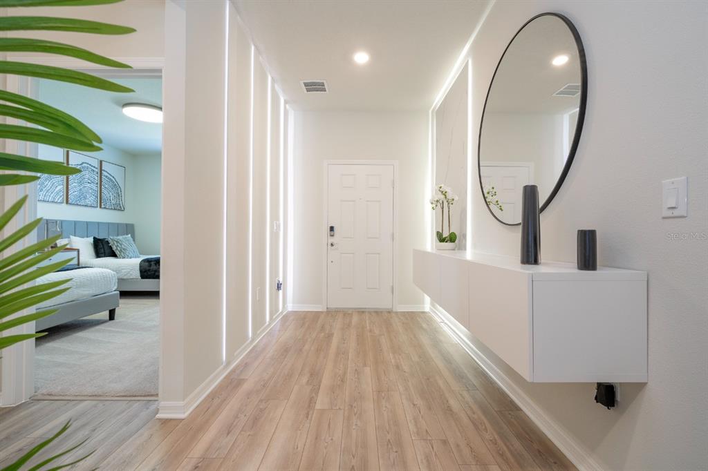 A bright entryway features light wood flooring, vertical wall lighting, and a floating white console — 4117 LANA AVENUE, DAVENPORT, FL