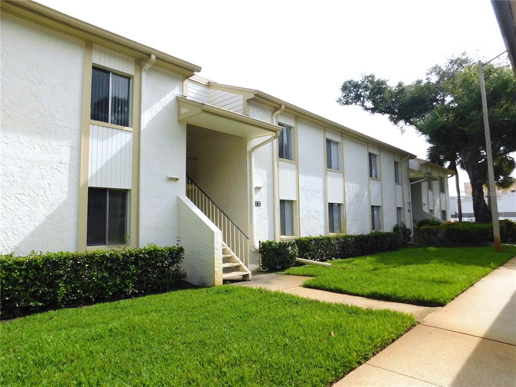 A two-story apartment building with white stucco walls, tan trim, and a concrete walkway — 105 PALMETTO COURT, OLDSMAR, FL