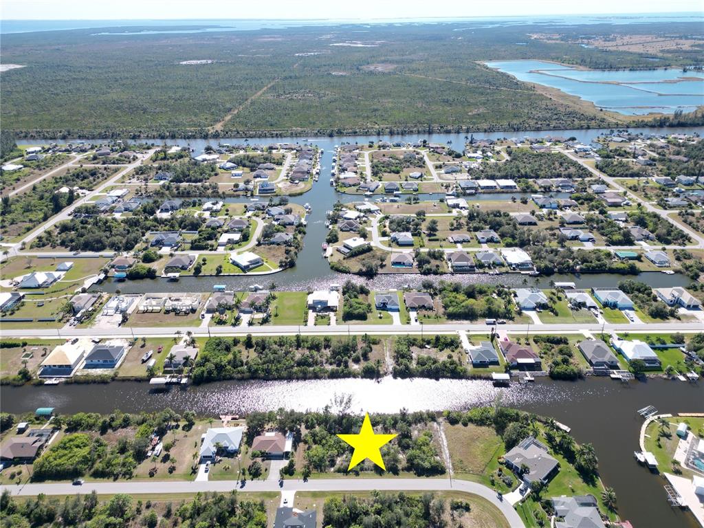 An aerial view shows a vacant waterfront lot marked with a yellow star — 15706 STUART CIRCLE, PORT CHARLOTTE, FL