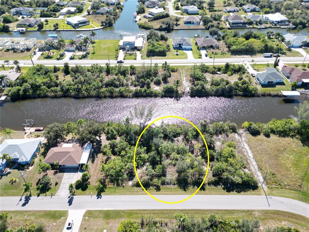 An aerial view shows a vacant, wooded residential lot highlighted by a yellow circle — 15706 STUART CIRCLE, PORT CHARLOTTE, FL