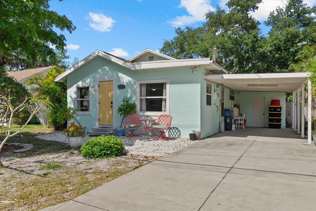 A light green single-story house features a yellow front door, a carport, and gravel landscaping — 4111 SARASOTA AVENUE, SARASOTA, FL