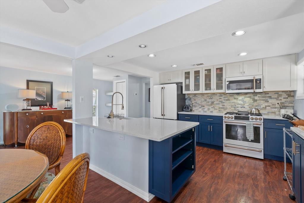 A kitchen features blue lower cabinets, white upper cabinets, a quartz island, and wood flooring — 4111 SARASOTA AVENUE, SARASOTA, FL