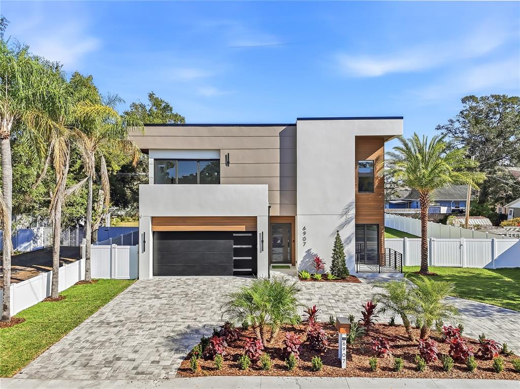A modern two-story house features a flat roof, a garage, and a paved driveway — 6907 N BOULEVARD, TAMPA, FL