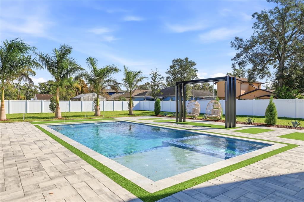 A backyard swimming pool with a tanning ledge, spa, and hanging chairs under a pergola — 6907 N BOULEVARD, TAMPA, FL