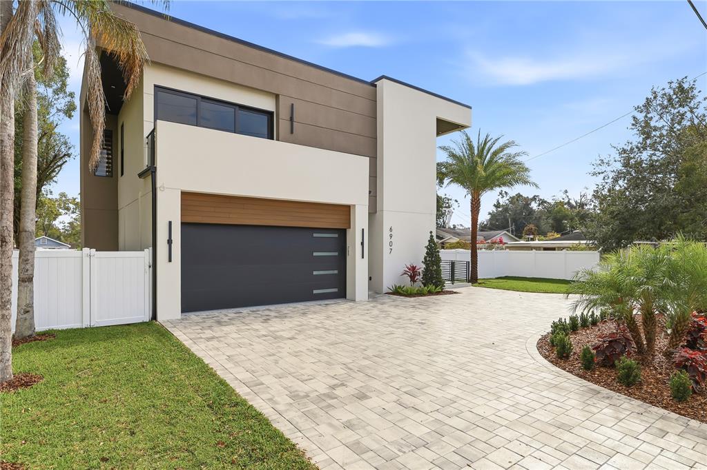 A modern two-story house features a paved driveway, a garage, and a white fence — 6907 N BOULEVARD, TAMPA, FL