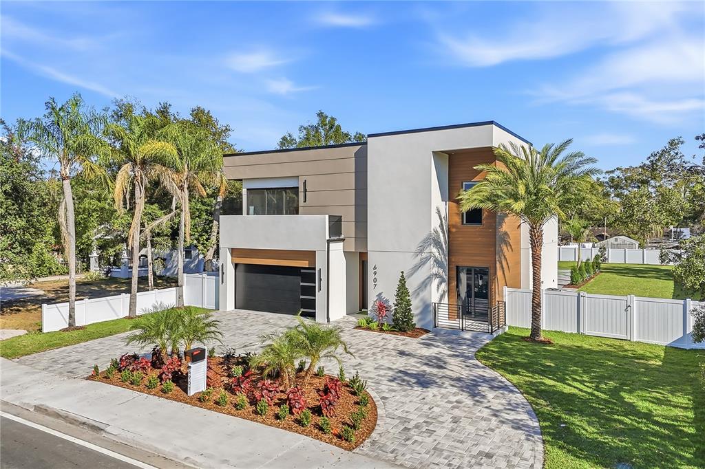 A modern two-story house with a paved driveway, palm trees, and a white fence — 6907 N BOULEVARD, TAMPA, FL