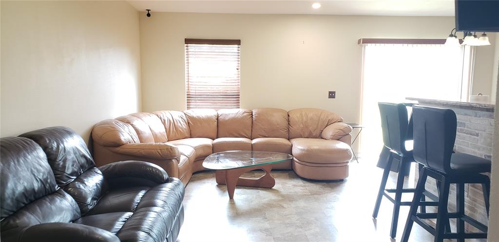 A living room features a tan sectional sofa, a dark leather loveseat, and bar stools — 4560 ASHBURN SQUARE DRIVE, TAMPA, FL