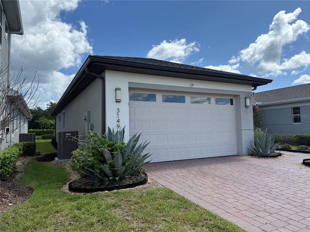 A detached garage with a white door, stucco exterior, and a brick paver driveway — 3149 SONGBIRD CIRCLE, ST CLOUD, FL