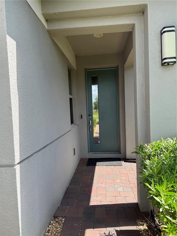 A teal front door with a vertical window sits at the end of a paver walkway — 3149 SONGBIRD CIRCLE, ST CLOUD, FL