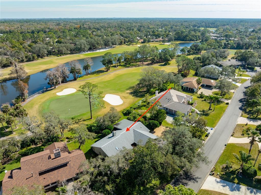 An aerial view shows a house with a gray roof situated beside a golf course — 507 BOXWOOD LANE, NEW SMYRNA BEACH, FL