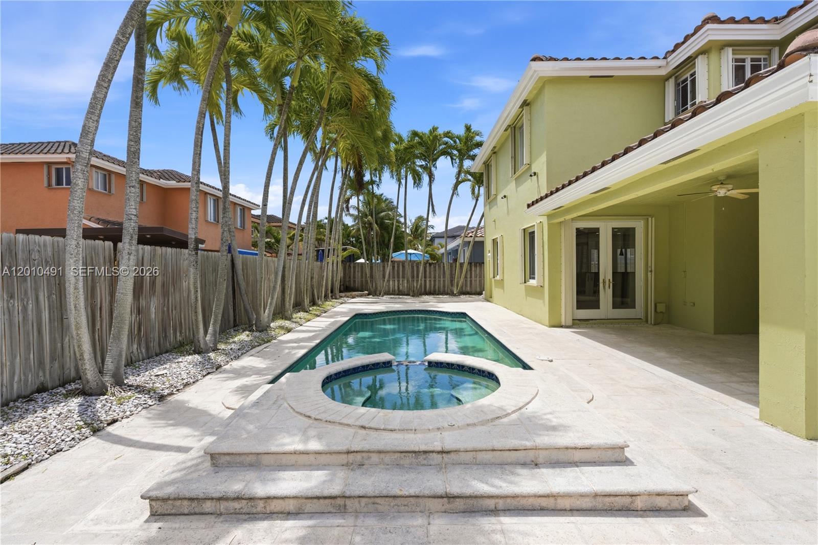 A backyard features a swimming pool, a raised hot tub, and palm trees beside a house — 15203 SW 142nd Ave, Miami FL 33177, MIAMI, FL