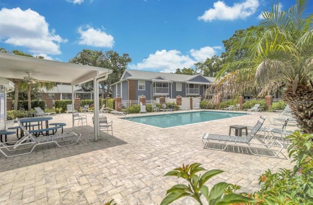 A swimming pool with lounge chairs and a covered patio area in a residential complex — 5457 LAKE MARGARET DRIVE UNIT 19-1, ORLANDO, FL