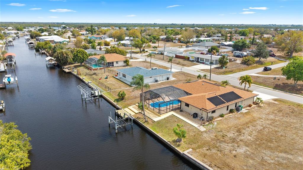 An aerial view shows a waterfront house with a pool cage and private boat dock — 27248 SAN MARINO DRIVE, PUNTA GORDA, FL