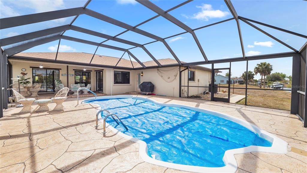 A screened-in patio features a swimming pool with a blue cover and patio furniture — 27248 SAN MARINO DRIVE, PUNTA GORDA, FL