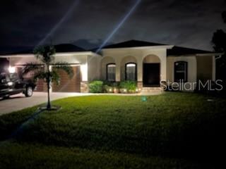 A single-story house with a garage and arched entryway at night — 13376 YAGER LANE, PORT CHARLOTTE, FL