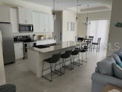 A modern kitchen features white cabinets, stainless steel appliances, and a large island with bar seating — 13376 YAGER LANE, PORT CHARLOTTE, FL