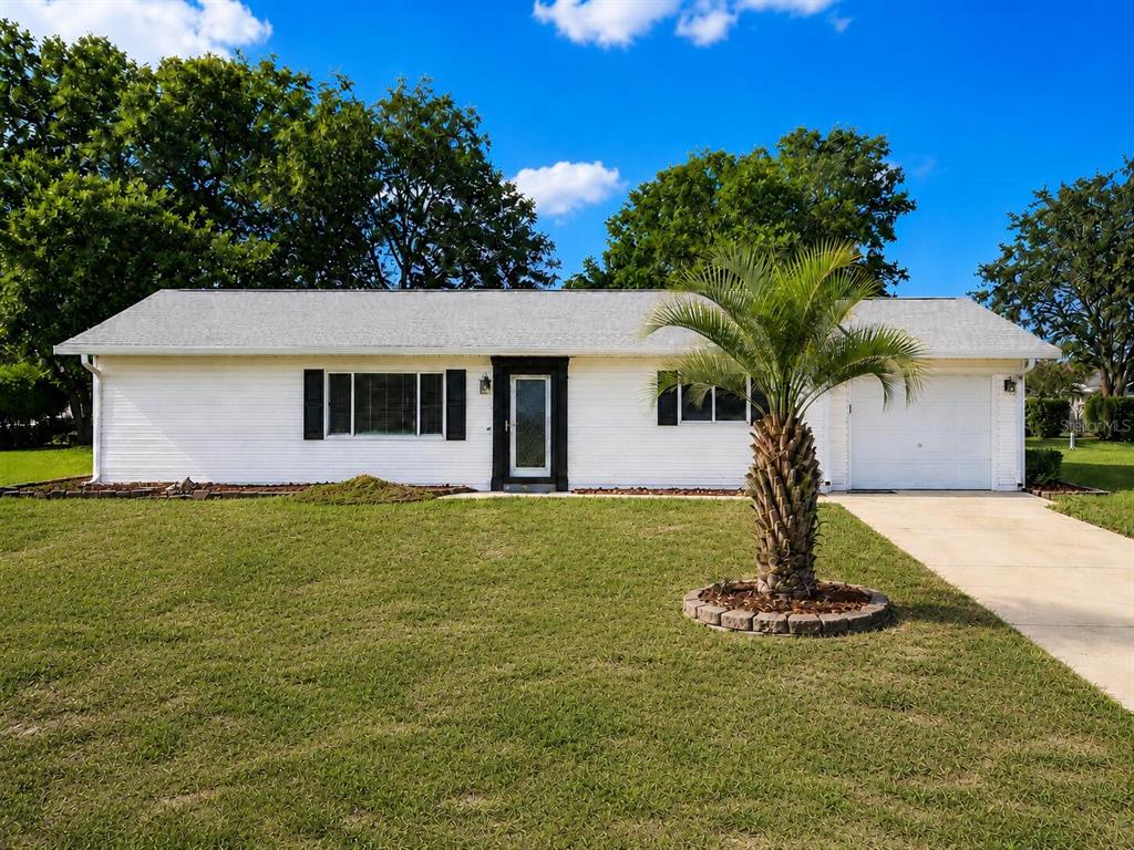 A white, single-story ranch-style house features black shutters, a front door, and a palm tree — 6286 SW 110TH STREET, OCALA, FL