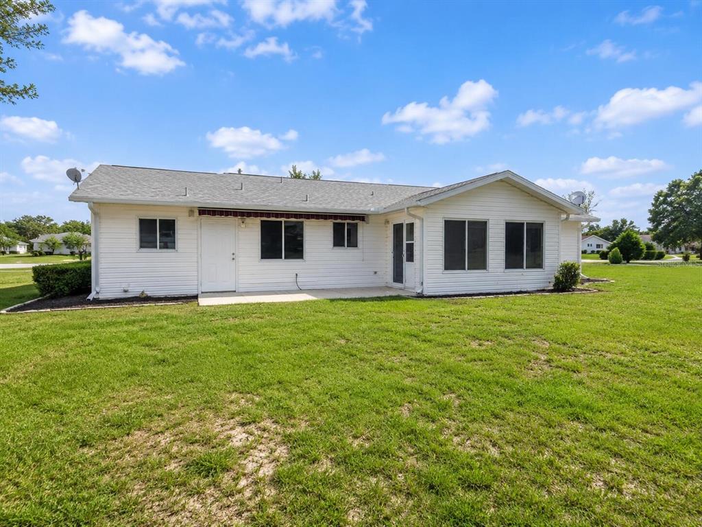 The exterior of a white, single-story house features a concrete patio and a grassy yard — 6286 SW 110TH STREET, OCALA, FL