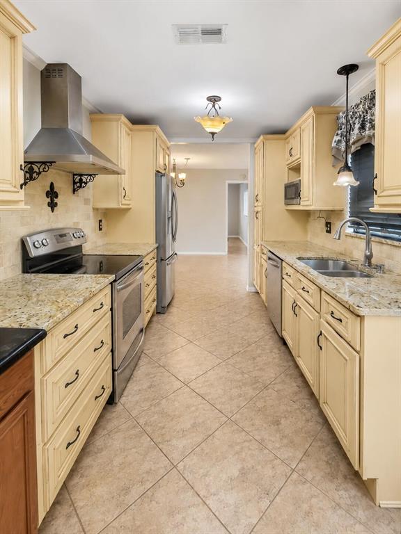 A galley kitchen features cream-colored cabinets, granite countertops, stainless steel appliances, and tile flooring — 6286 SW 110TH STREET, OCALA, FL
