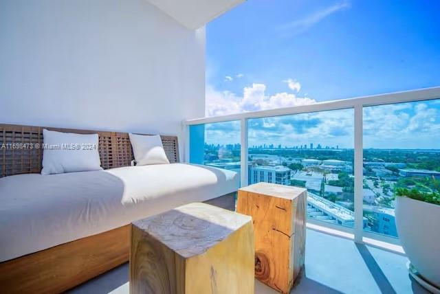 A balcony features a wooden daybed with white pillows and two wooden block side tables — 102 24th St # 1021, Miami Beach FL 33139, MIAMI BEACH, FL