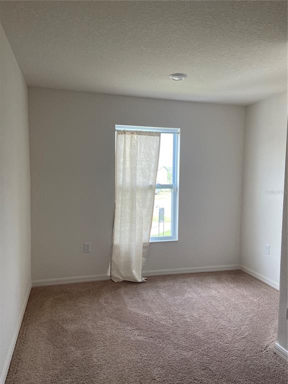 An empty bedroom with beige carpet, white walls, and a single window with a curtain — 1523 WYNFORD CIRCLE, TAVARES, FL