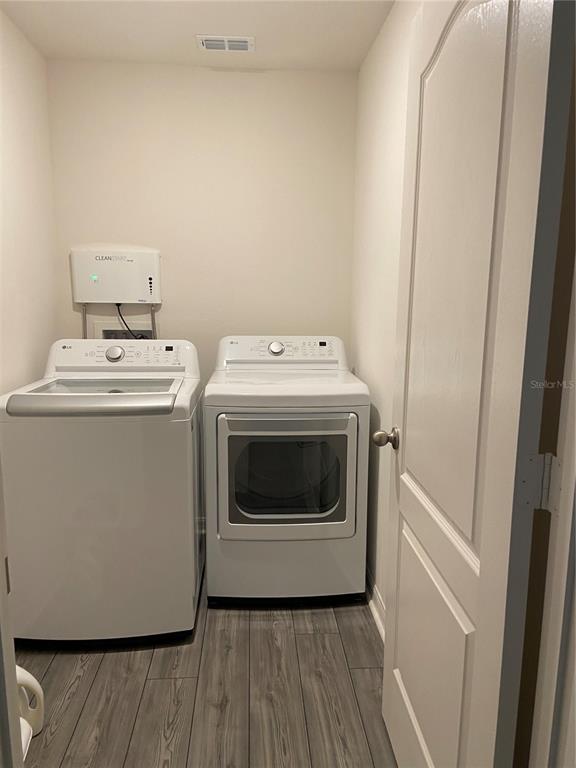 A laundry room features a white top-load washer and dryer on a gray wood-look floor — 1523 WYNFORD CIRCLE, TAVARES, FL