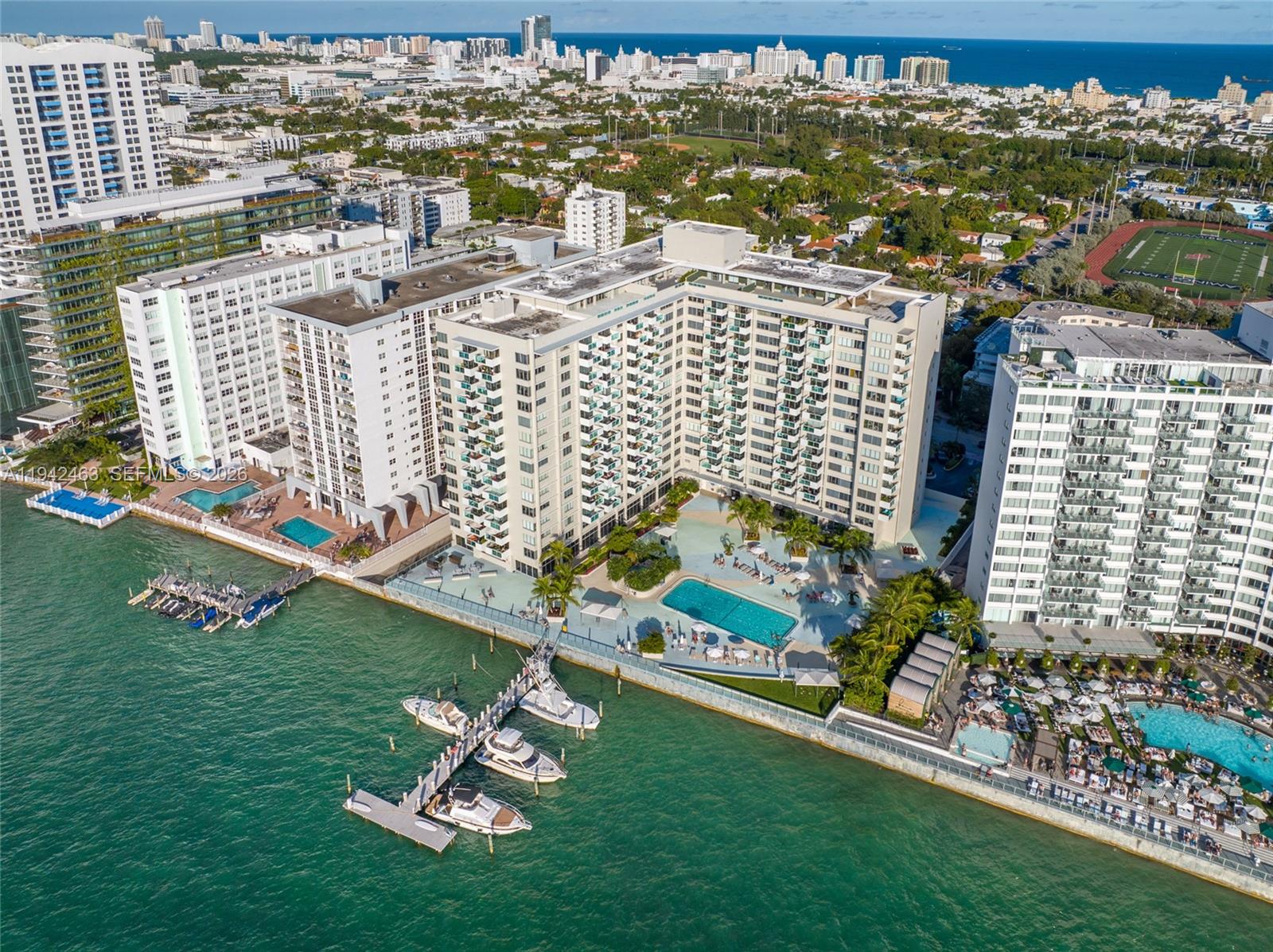 An aerial view shows waterfront high-rise apartment buildings with swimming pools and a boat dock — 1200 West Ave # 422, Miami Beach FL 33139, MIAMI BEACH, FL