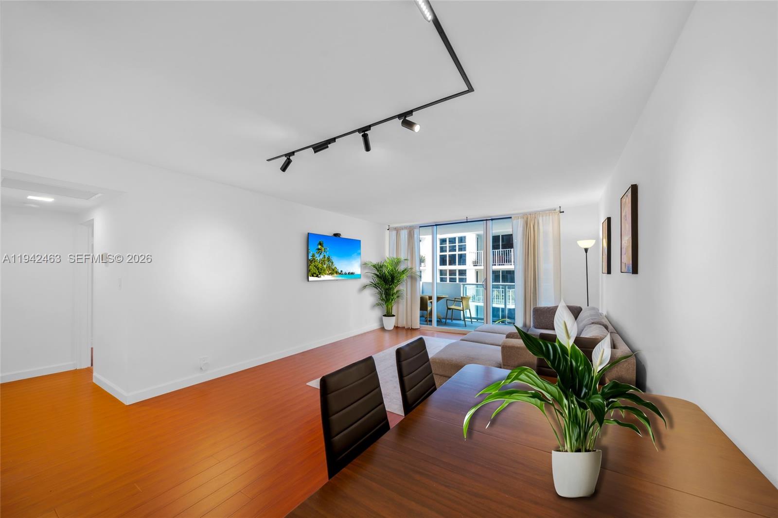 A living room with wood flooring, a wall-mounted television, and a balcony view — 1200 West Ave # 422, Miami Beach FL 33139, MIAMI BEACH, FL