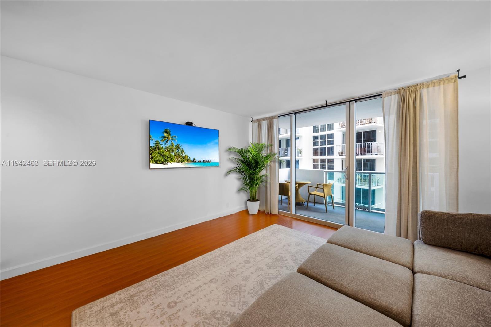 A living room features wood flooring, a wall-mounted television, a rug, and a balcony — 1200 West Ave # 422, Miami Beach FL 33139, MIAMI BEACH, FL
