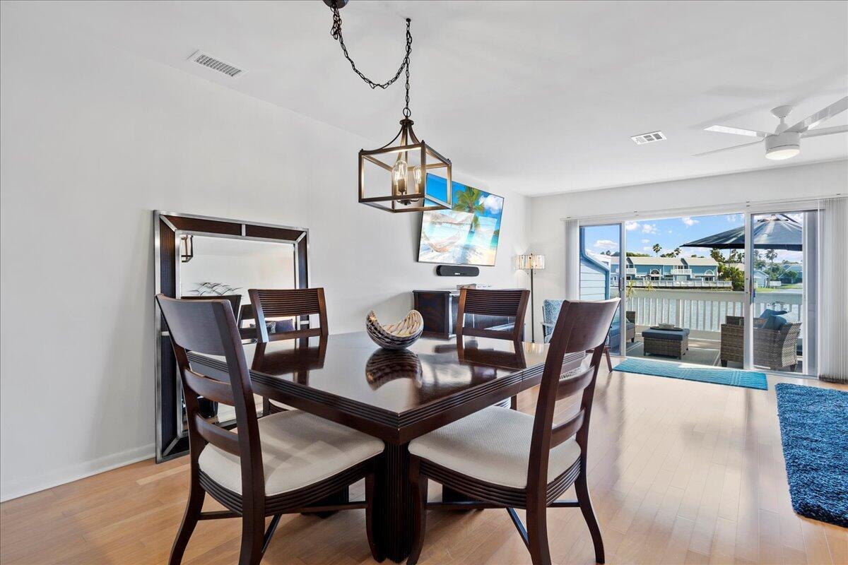 A dining area with a dark wood table and chairs sits before a sliding glass door — 1121 Ocean Dunes Circle, Jupiter FL 33477, JUPITER, FL