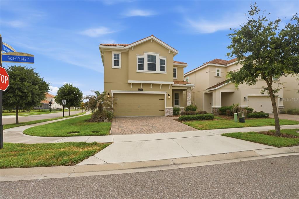 A two-story tan stucco house with a paved driveway and a two-car garage — 8700 PACIFIC DUNES DRIVE, DAVENPORT, FL