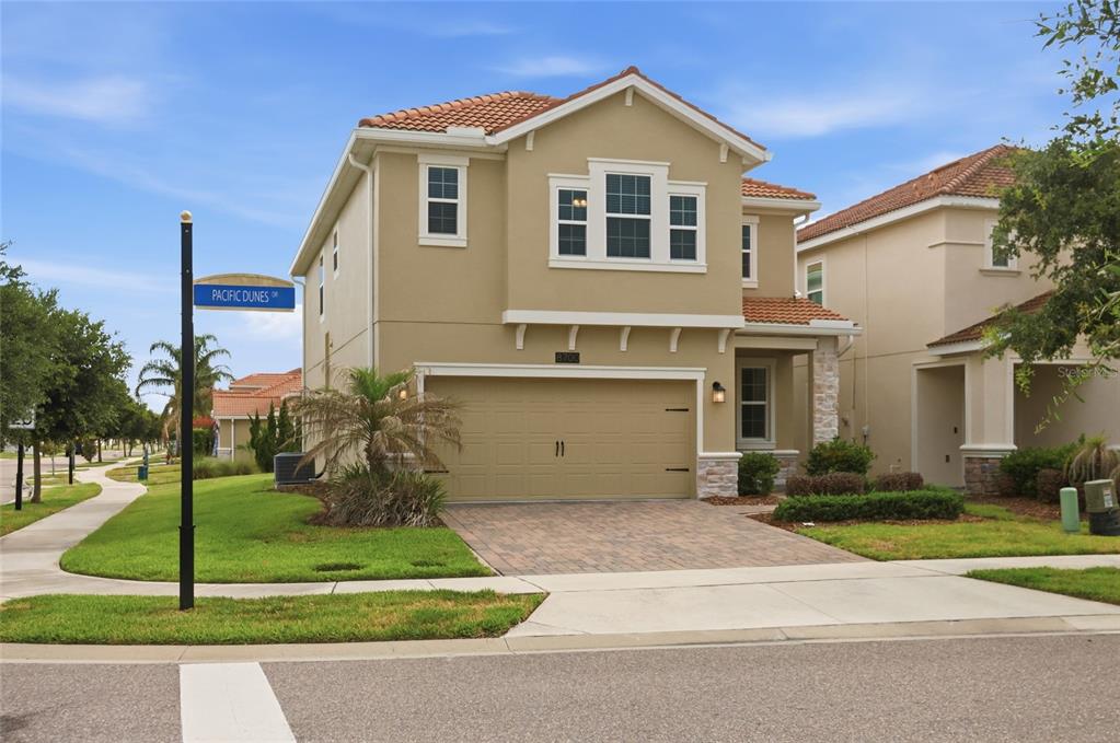 A two-story suburban house with a tan stucco exterior, tile roof, and a two-car garage — 8700 PACIFIC DUNES DRIVE, DAVENPORT, FL