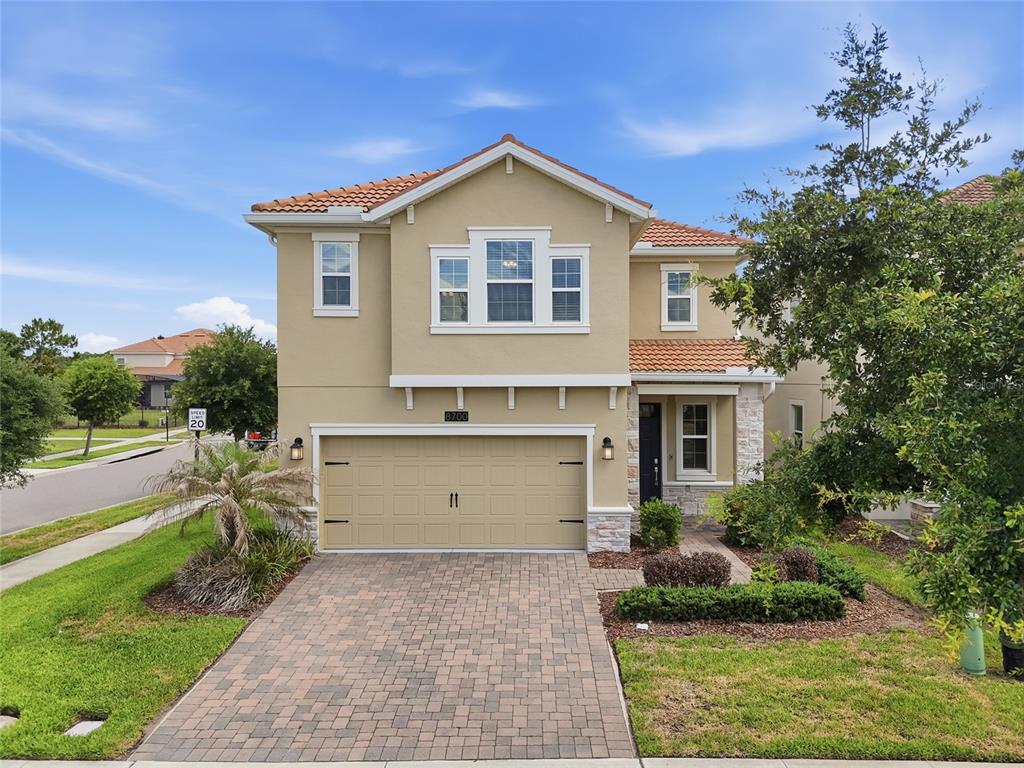 A two-story suburban house with a tan stucco exterior, tile roof, and paved driveway — 8700 PACIFIC DUNES DRIVE, DAVENPORT, FL