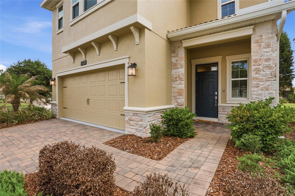 The exterior of a two-story home features a tan stucco facade, stone accents, and a garage — 8700 PACIFIC DUNES DRIVE, DAVENPORT, FL