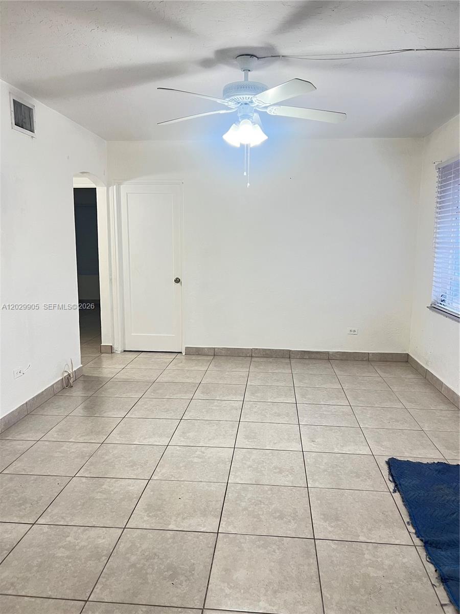 An empty room features white walls, a ceiling fan, and light-colored square floor tiles — 1401 E 8th Ave, Hialeah FL 33010, HIALEAH, FL
