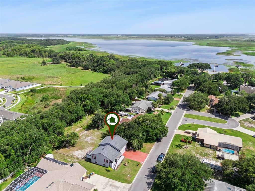 An aerial view shows a residential house with a gray roof near a large lake — 1869 KINGS POINT BOULEVARD, KISSIMMEE, FL