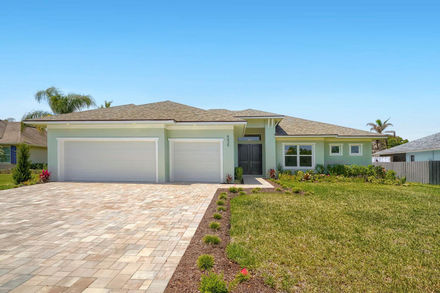 A single-story house with a light green exterior, a paved driveway, and a three-car garage — 6635 49th Court, Vero Beach FL 32967, VERO BEACH, FL