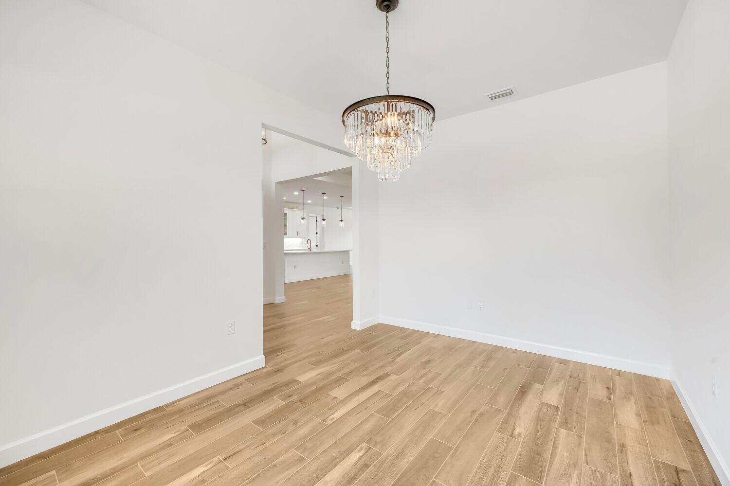 A dining room with light wood-look tile flooring and a crystal chandelier — 6635 49th Court, Vero Beach FL 32967, VERO BEACH, FL