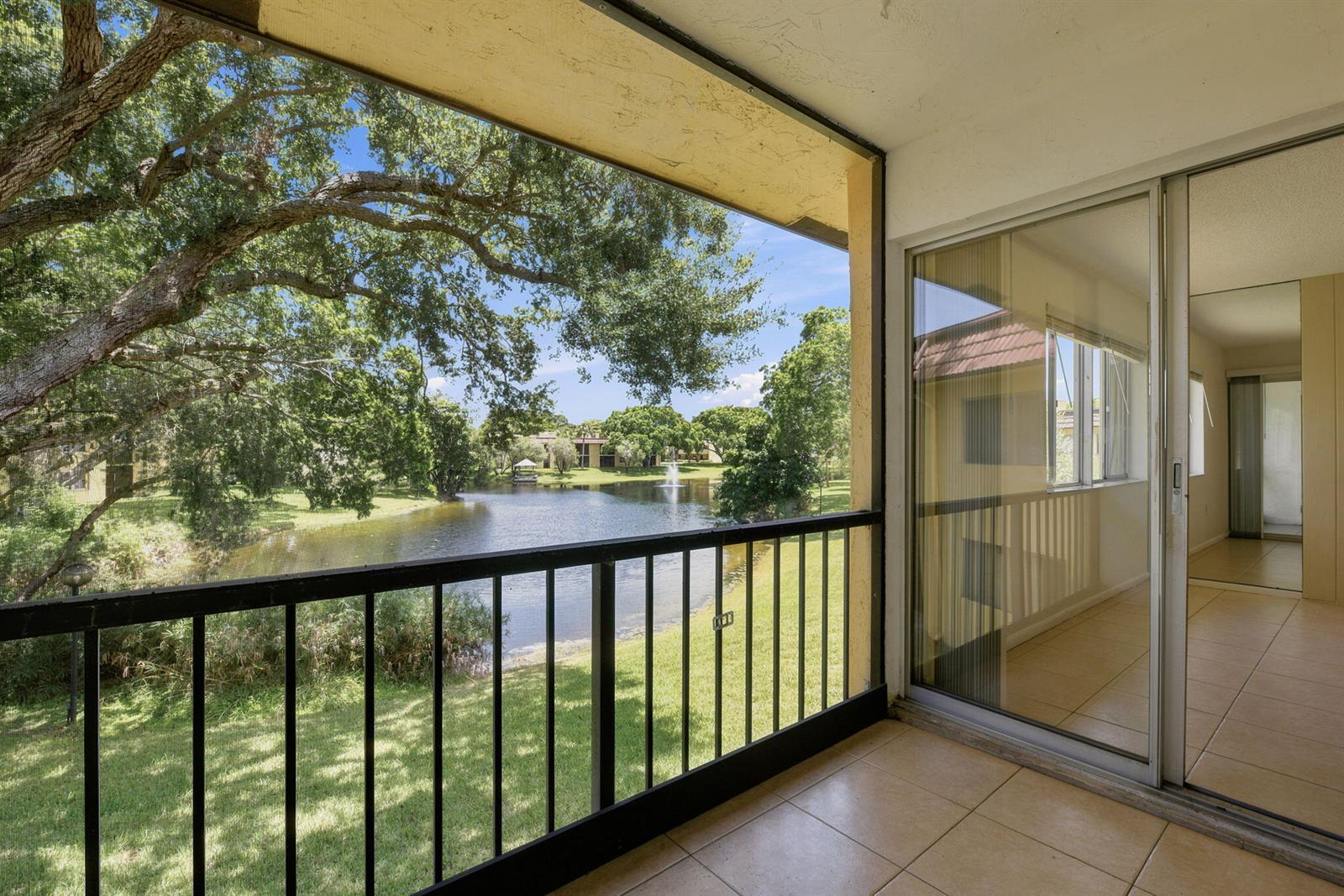 A tiled balcony with a black railing overlooks a lake and trees — 824 SW 9th Street Circle # 201, Boca Raton FL 33486, BOCA RATON, FL