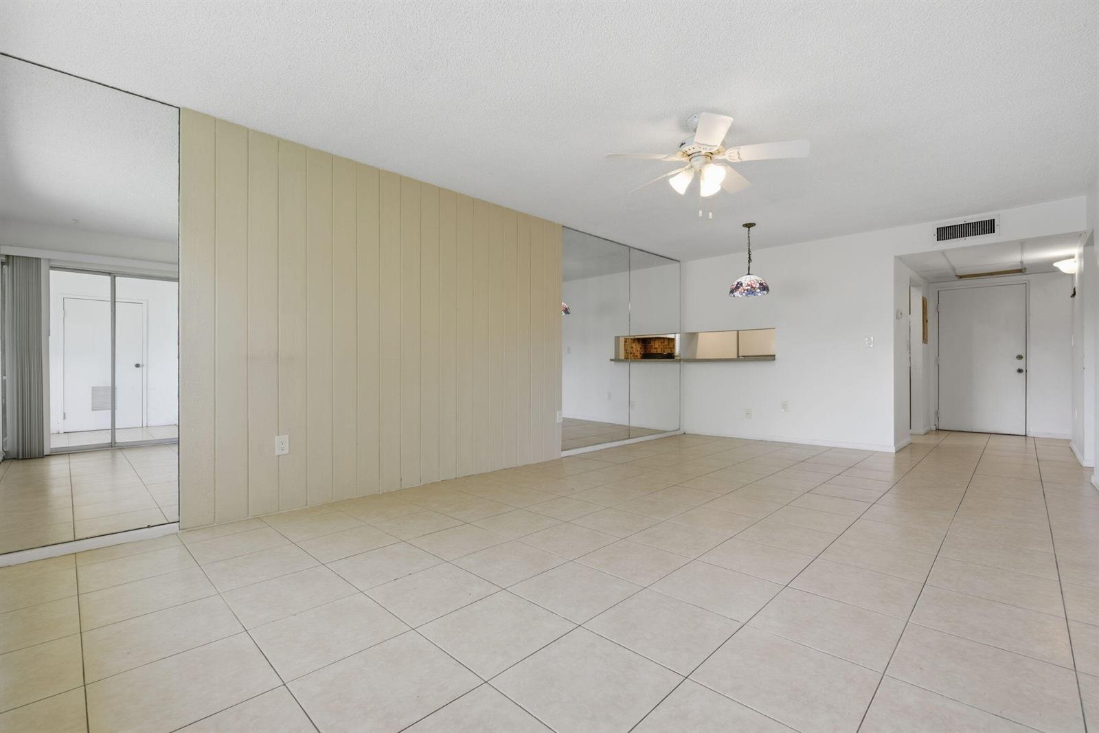 A living area features tiled floors, a paneled accent wall, mirrored surfaces, and a ceiling fan — 824 SW 9th Street Circle # 201, Boca Raton FL 33486, BOCA RATON, FL