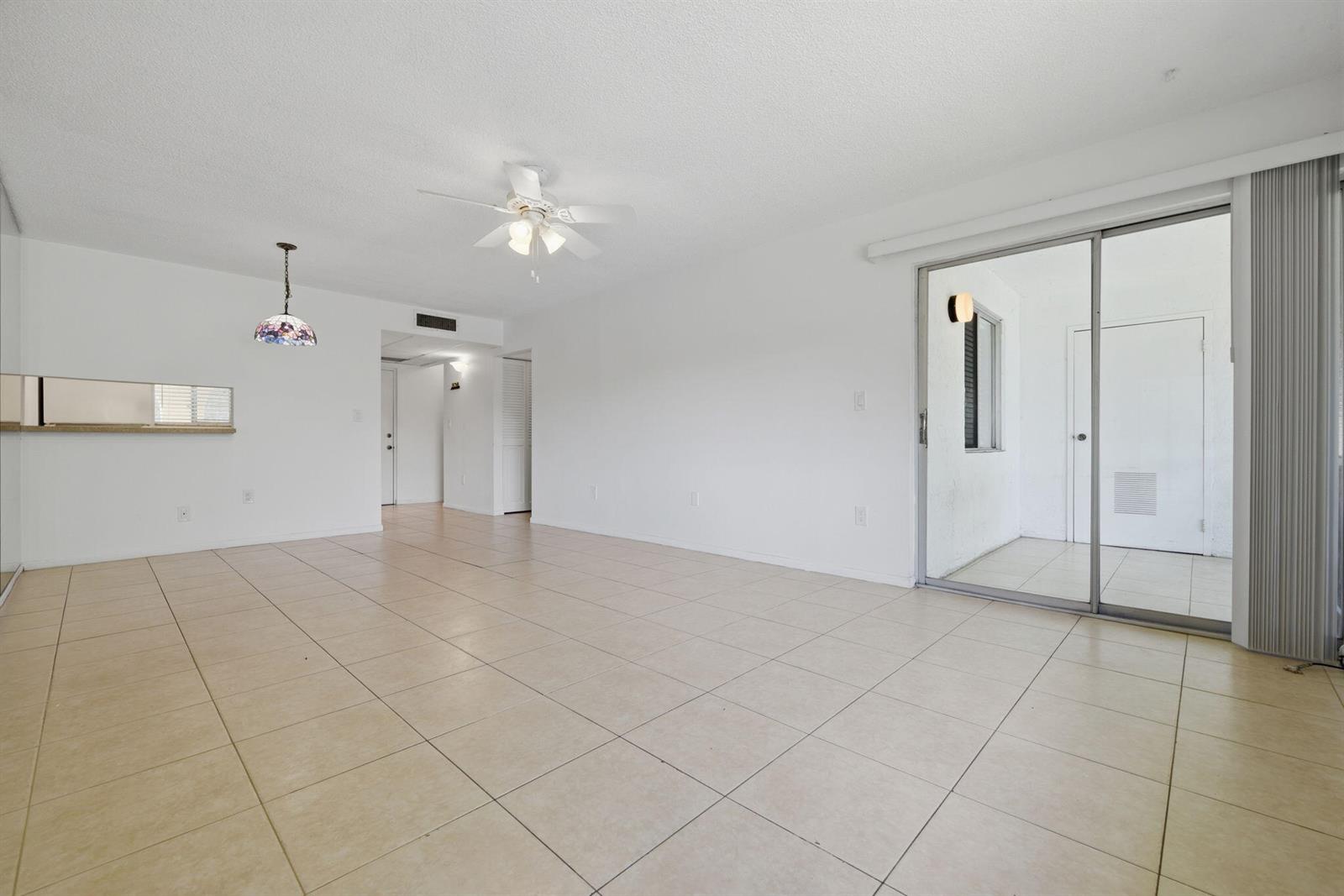 An empty room with white walls, beige tile flooring, a ceiling fan, and sliding doors — 824 SW 9th Street Circle # 201, Boca Raton FL 33486, BOCA RATON, FL