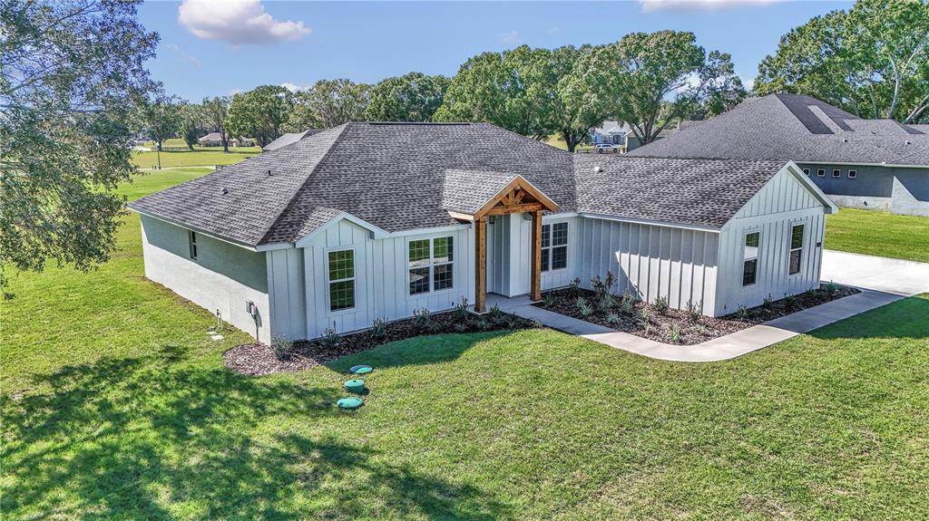 An exterior view of a white farmhouse-style home with a dark shingled roof and porch — 1916 NW 80TH STREET, OCALA, FL