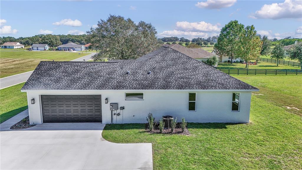 An exterior view of a white single-story house with a dark shingled roof and garage — 1916 NW 80TH STREET, OCALA, FL