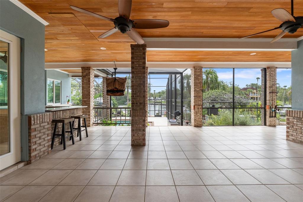 A covered outdoor patio features a tiled floor, brick columns, a wood ceiling, and screen enclosures — 6936 RIVER ROAD, NEW PORT RICHEY, FL