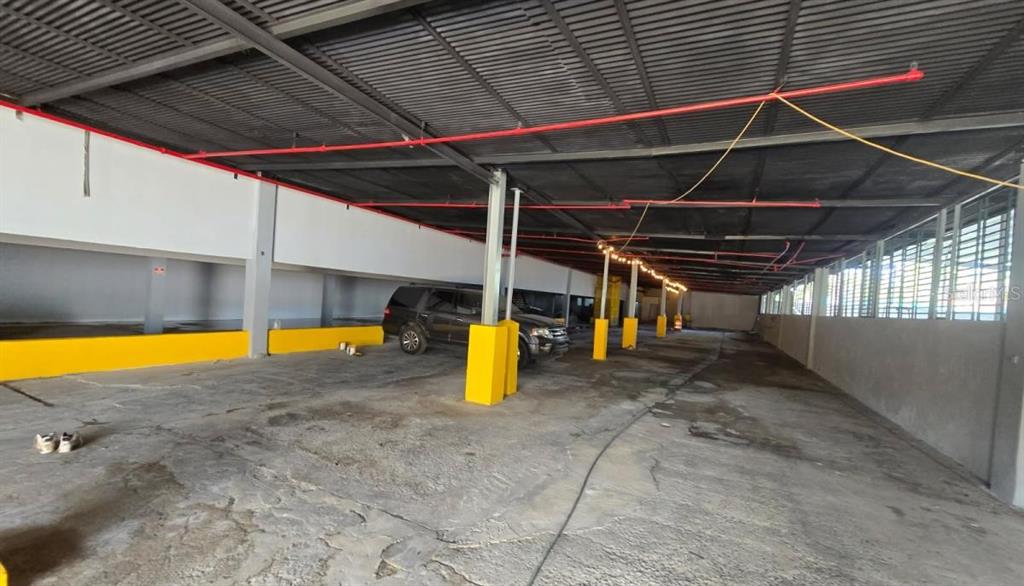 A covered parking garage features concrete flooring, yellow support pillars, and exposed red fire pipes — PR 185 Km. 66 INT PR 3, CANOVANAS, PR