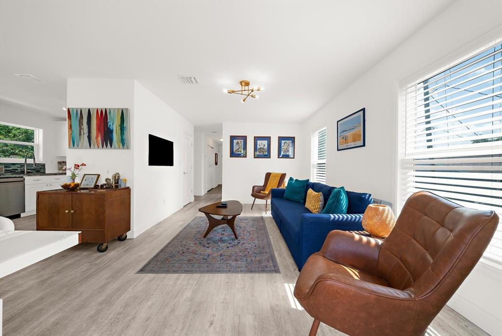 A living room features a blue sofa, a brown leather armchair, and light wood flooring — 2375 BAHIA VISTA STREET, SARASOTA, FL