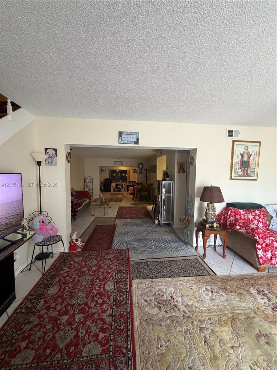 A living room with tile floors, multiple area rugs, and an open doorway to another room — 1727 NW 80th Ave # H, Margate FL 33063, MARGATE, FL