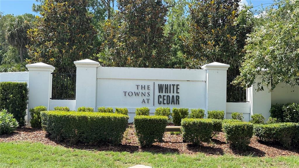 A white community entrance sign reads The Towns at White Cedar surrounded by green landscaping — 302 CEDAR BARK LANE, SANFORD, FL