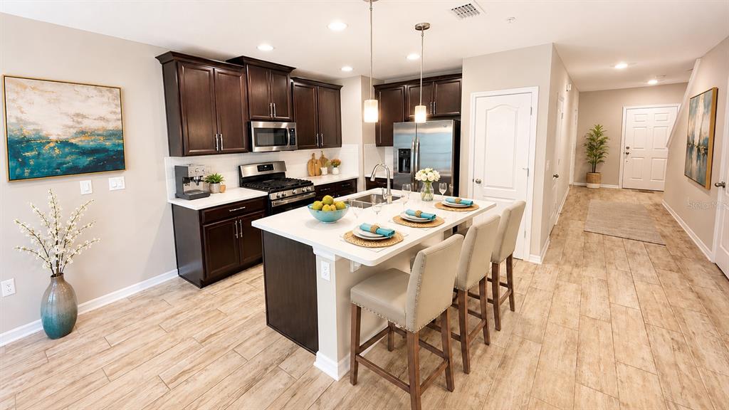 A kitchen with dark wood cabinets, a white island, and light wood-look tile flooring — 302 CEDAR BARK LANE, SANFORD, FL